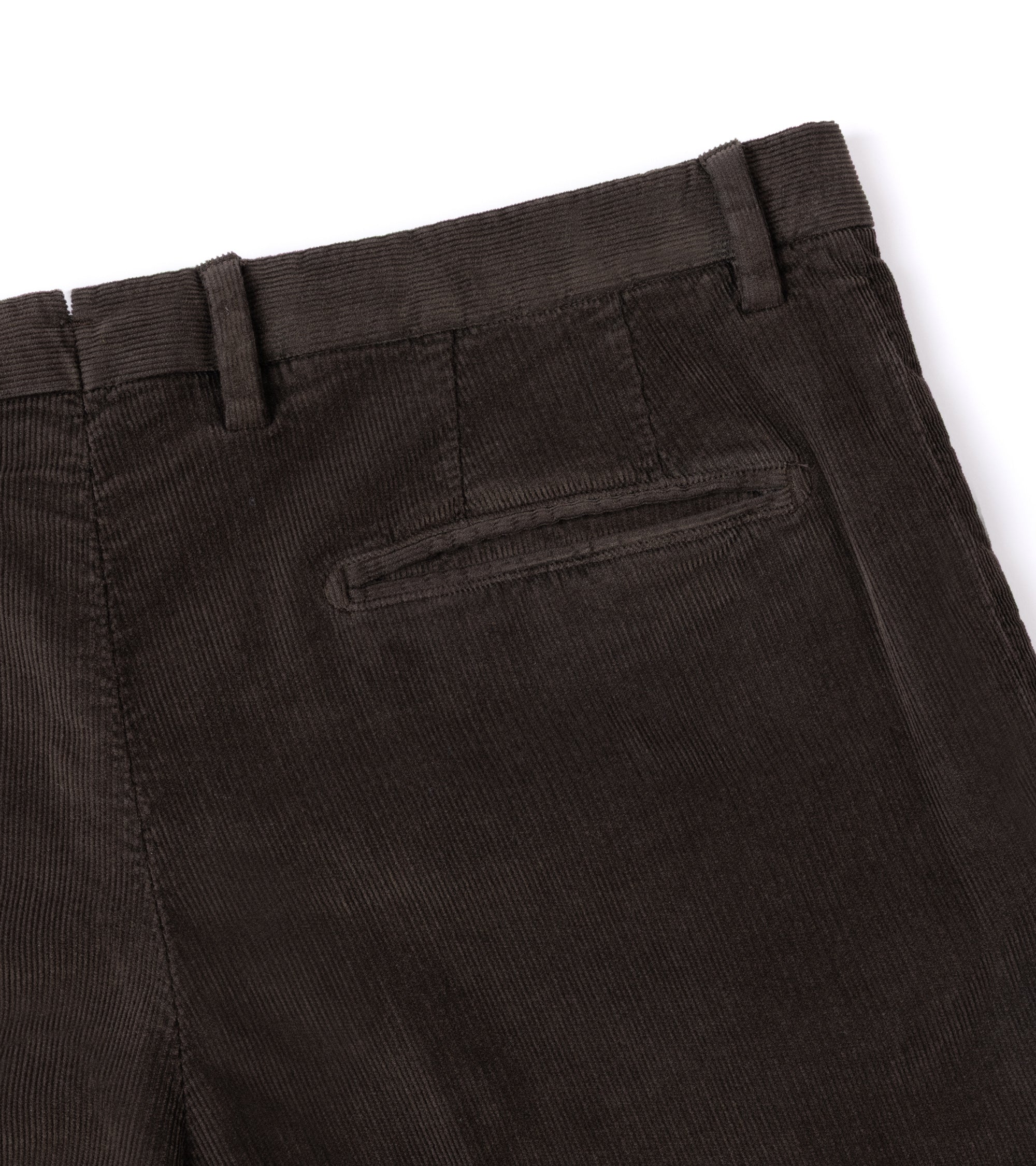 Close-up of the back waistband and pocket area of dark brown corduroy trousers on a white background.