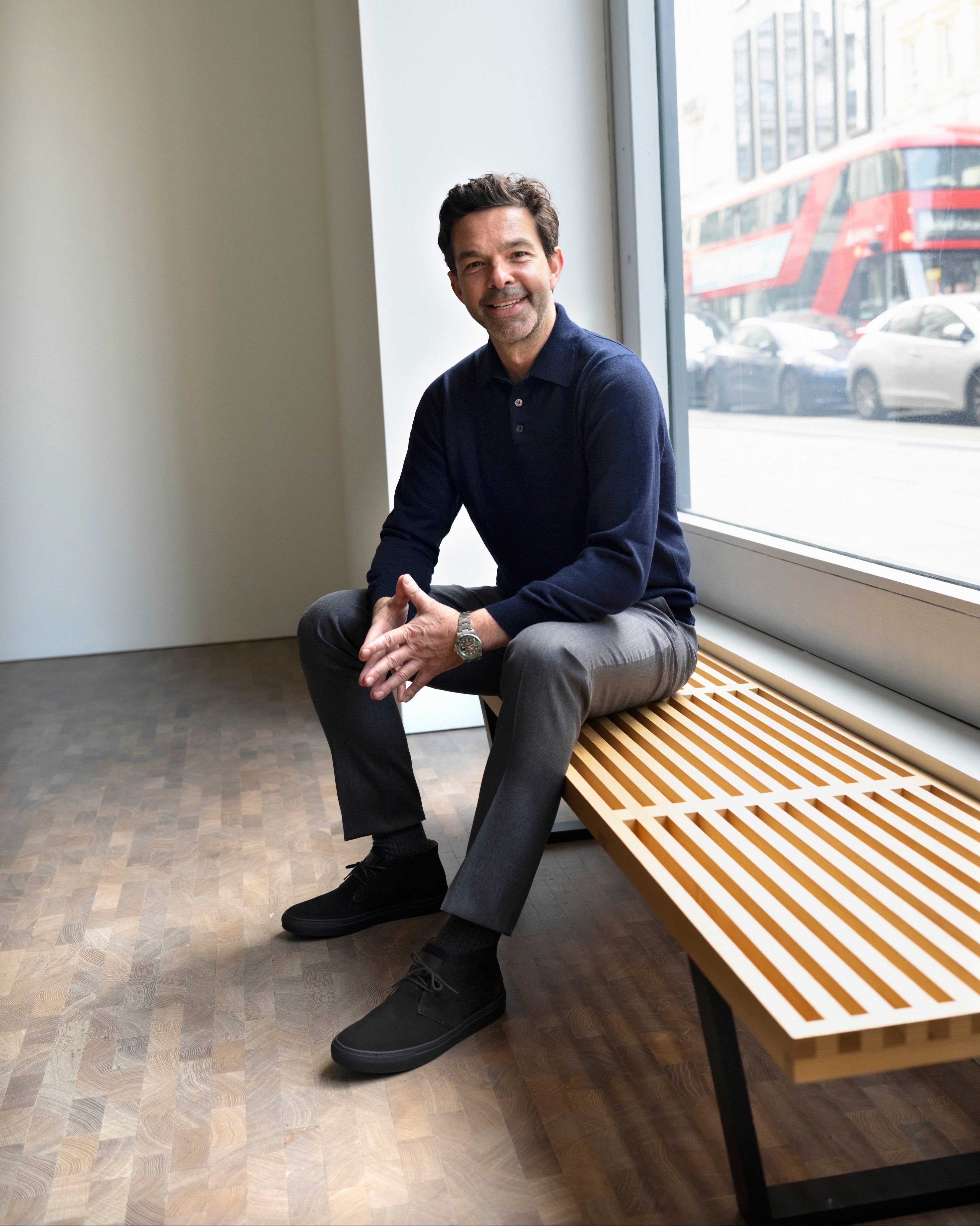 Man sitting on a wooden bench by a window with a cityscape view