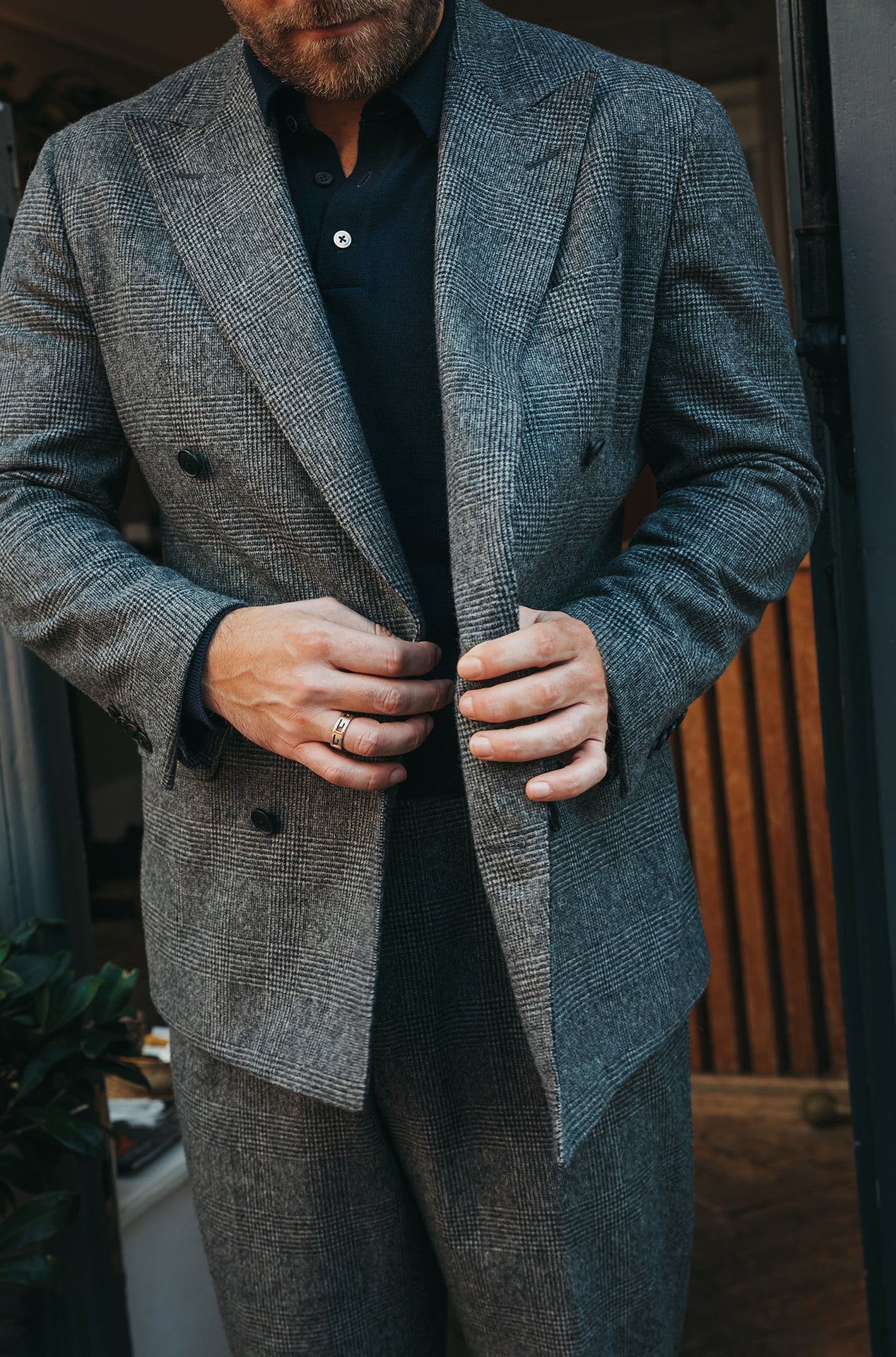 Man wearing a gray textured double breasted suit jacket with a blurred background