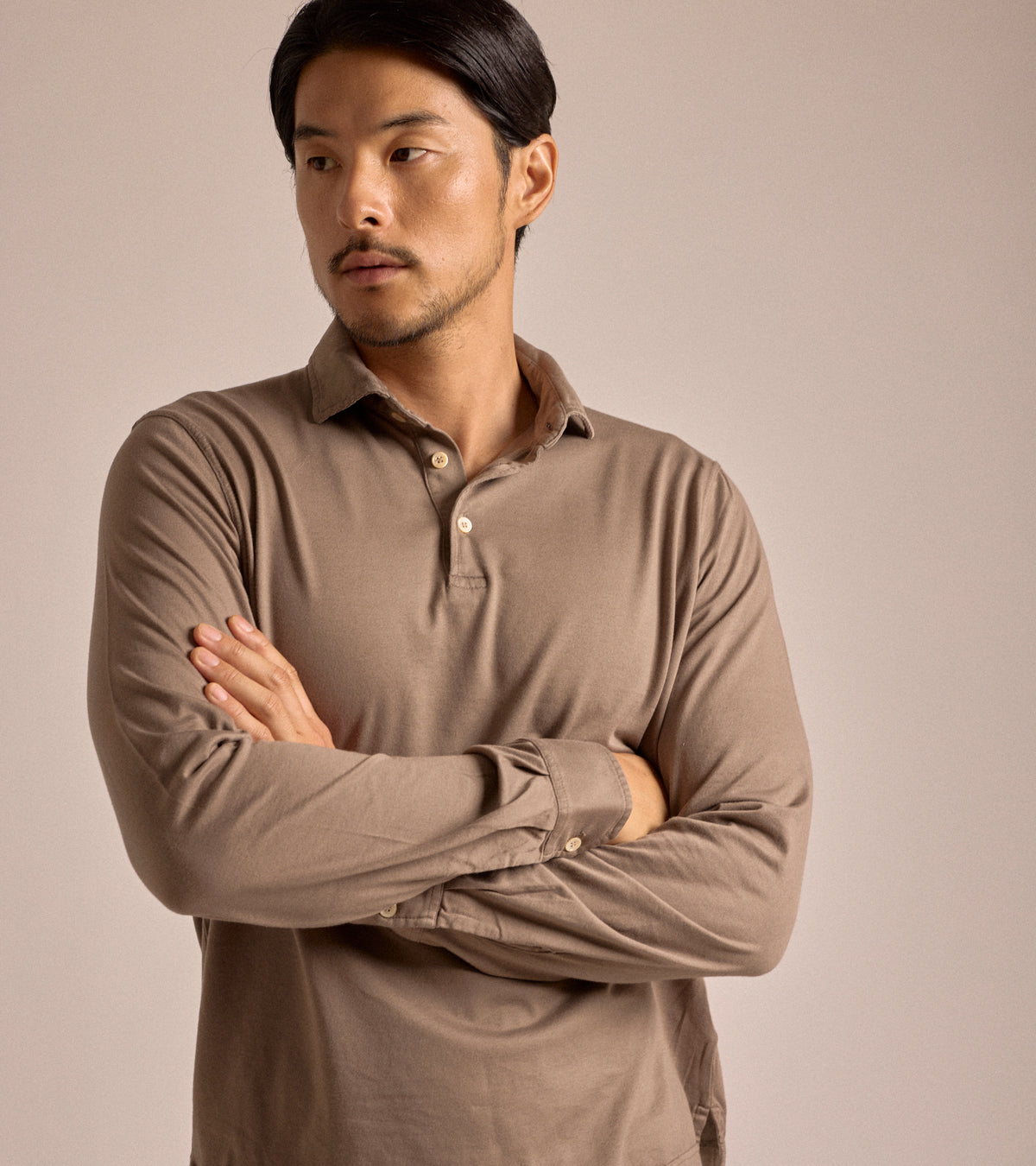 Model wearing the Fedeli Zero Cotton Jersey Long Sleeve Polo in dark greige. Front view with his arms crossed.