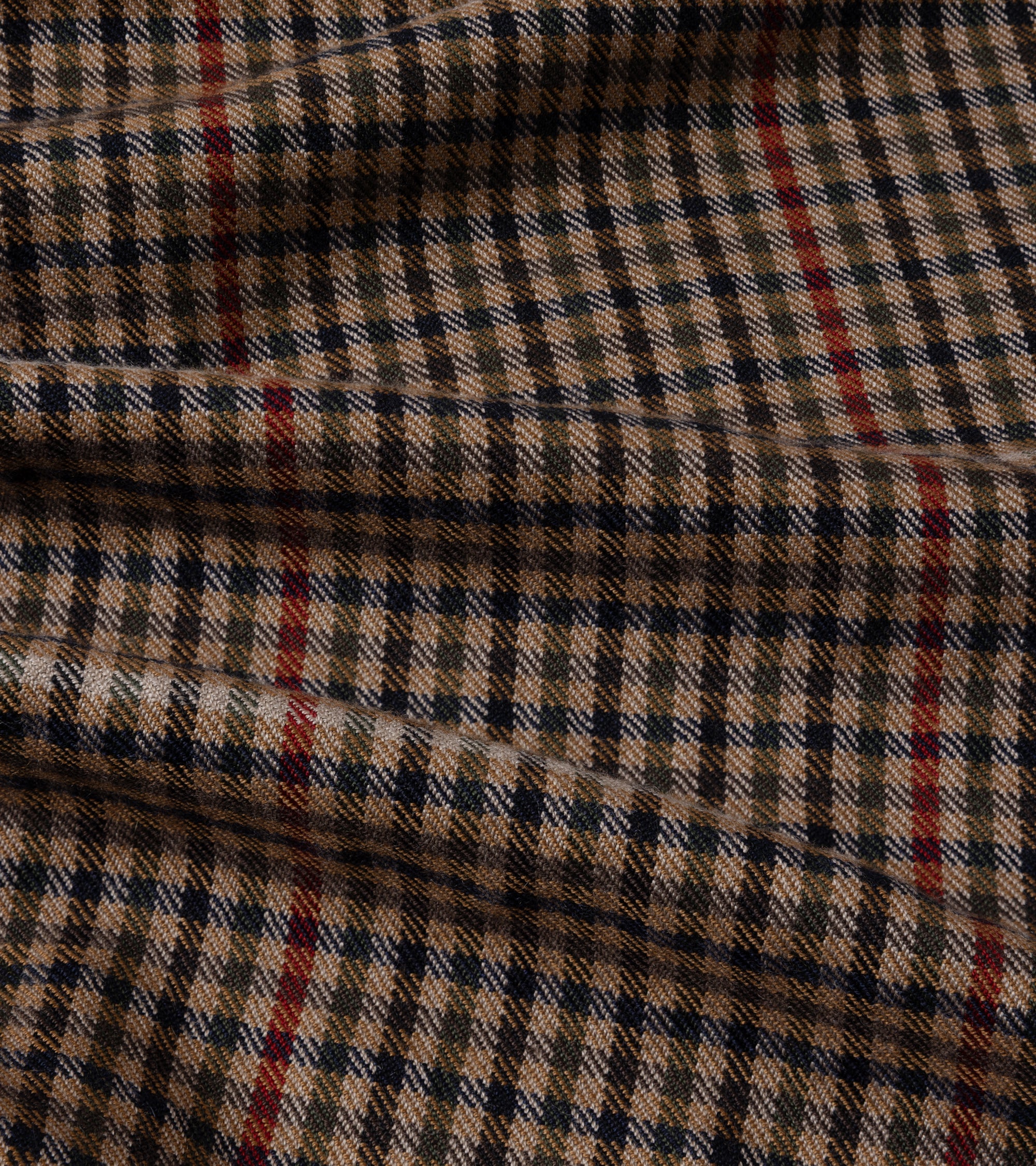 A close-up of a classic windowpane plaid fabric in beige, brown, and black, featuring thin red accent stripes.