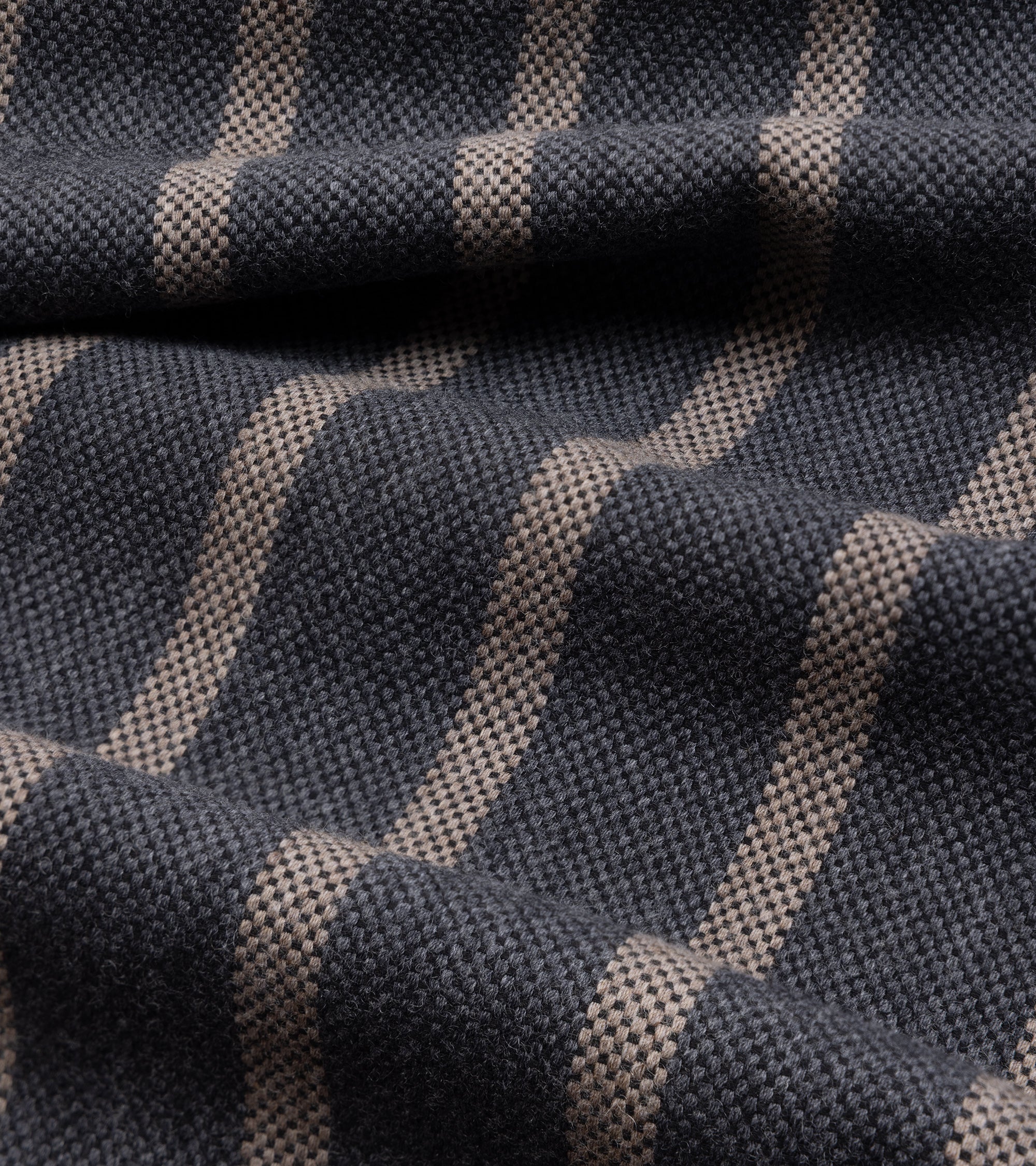 A close-up of woven fabric with a dark charcoal gray base and vertical stripes in a warm beige or taupe tone.