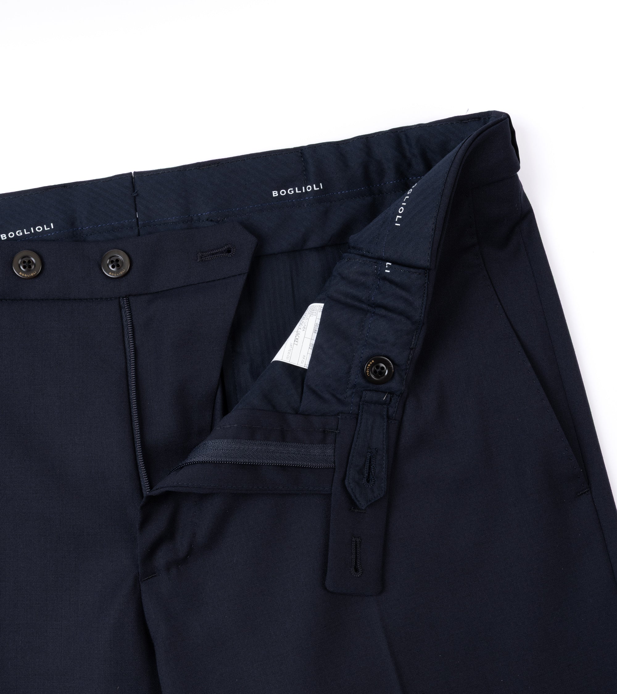 Close-up of dark navy trousers showing the waistband, button closure and zip fly.