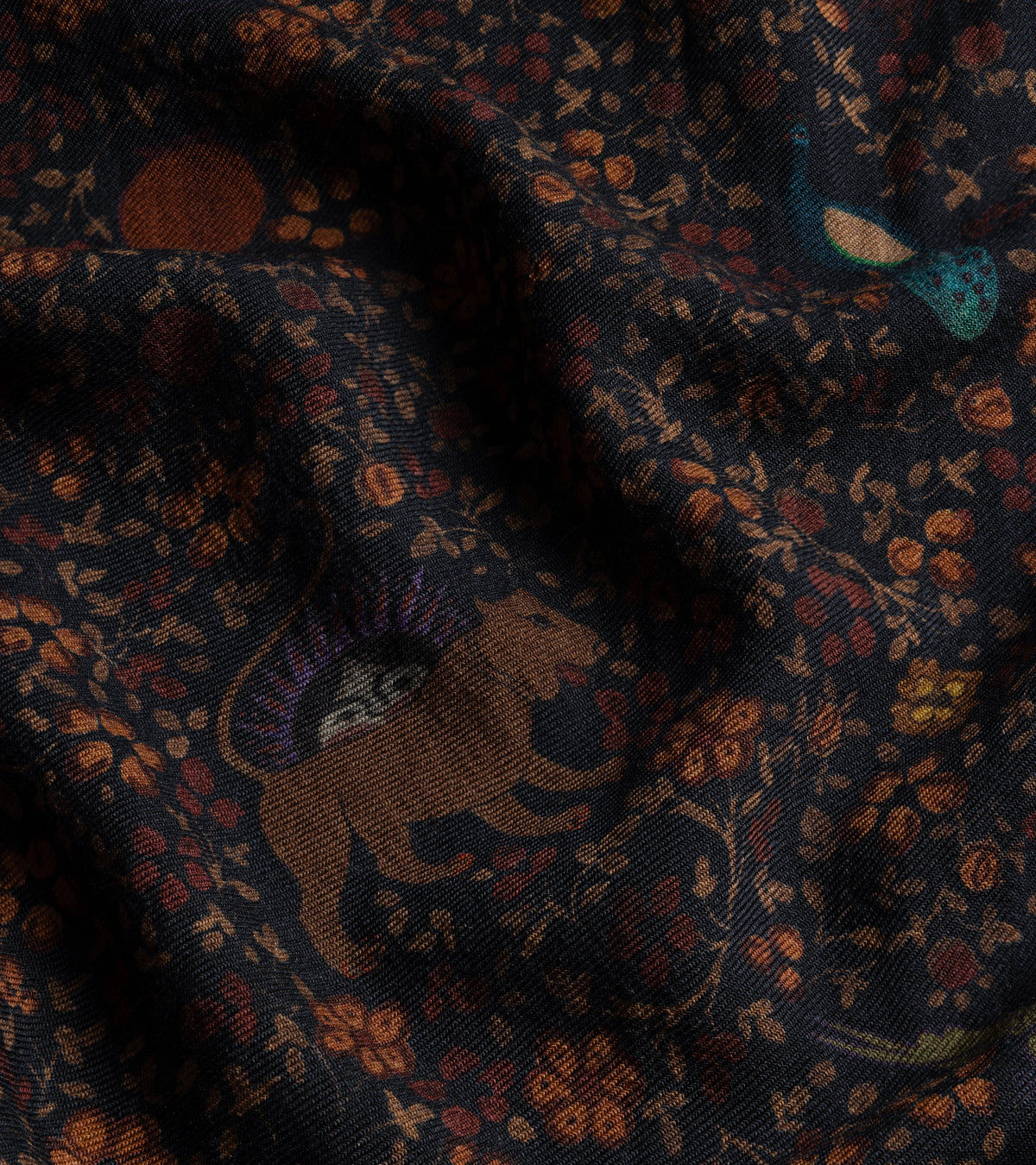 A close-up of the De Bonne Facture Ispahan Folk Pattern Soft Wool Scarf in Green, showing the fabric texture and design pattern.