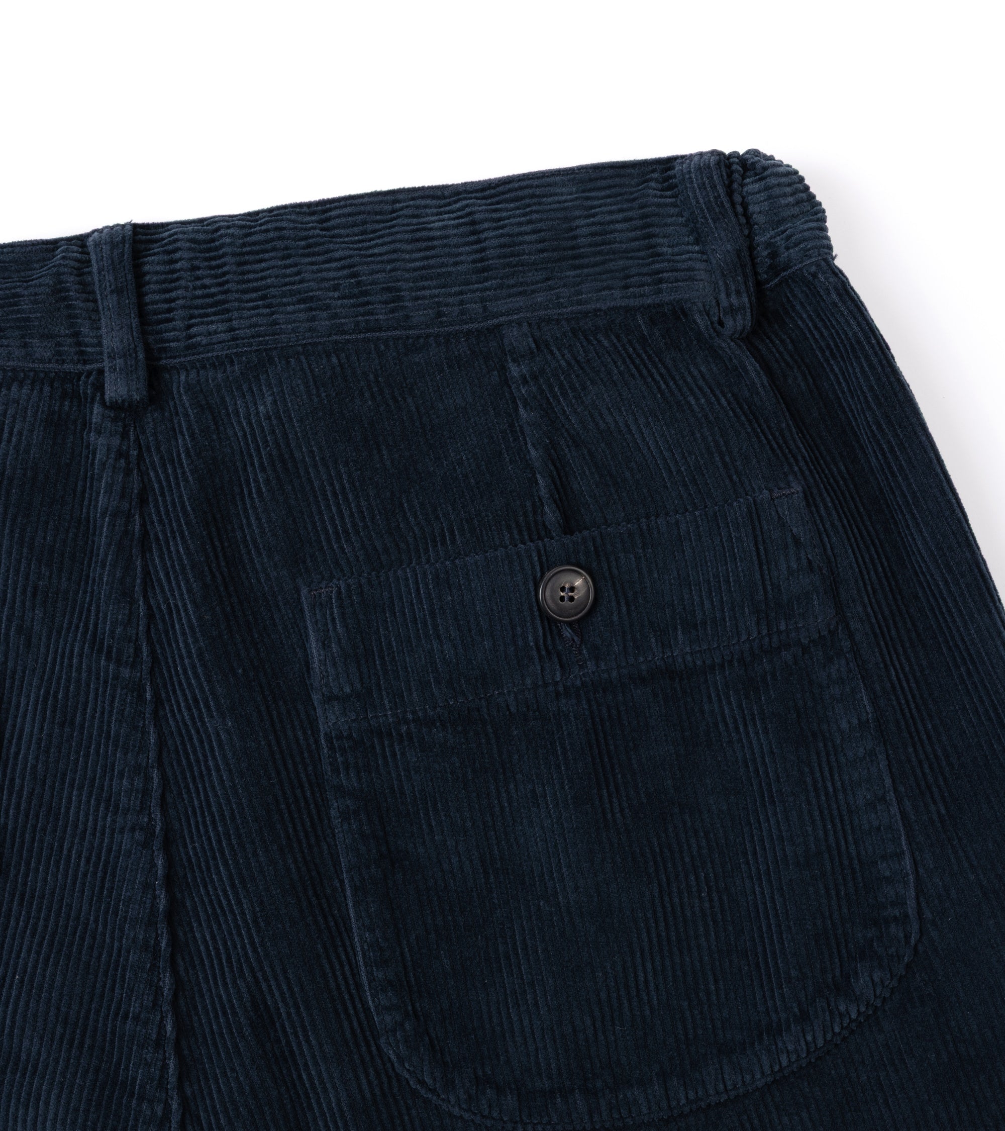 Close-up of the back waistband and pocket area of dark navy corduroy pants, showing the ribbed fabric texture and a single buttoned back pocket.