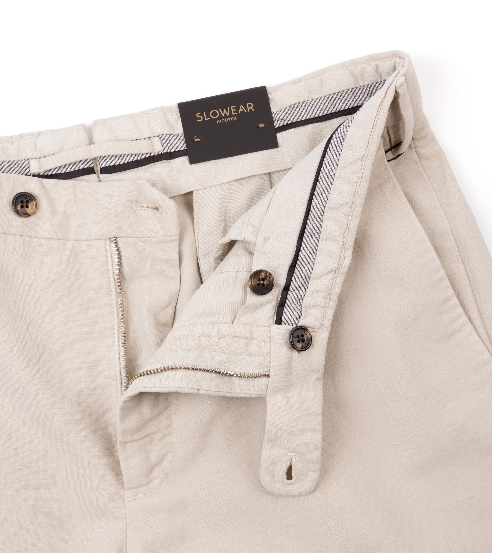 Close-up of cream pants showing the waistband, zipper and button details.