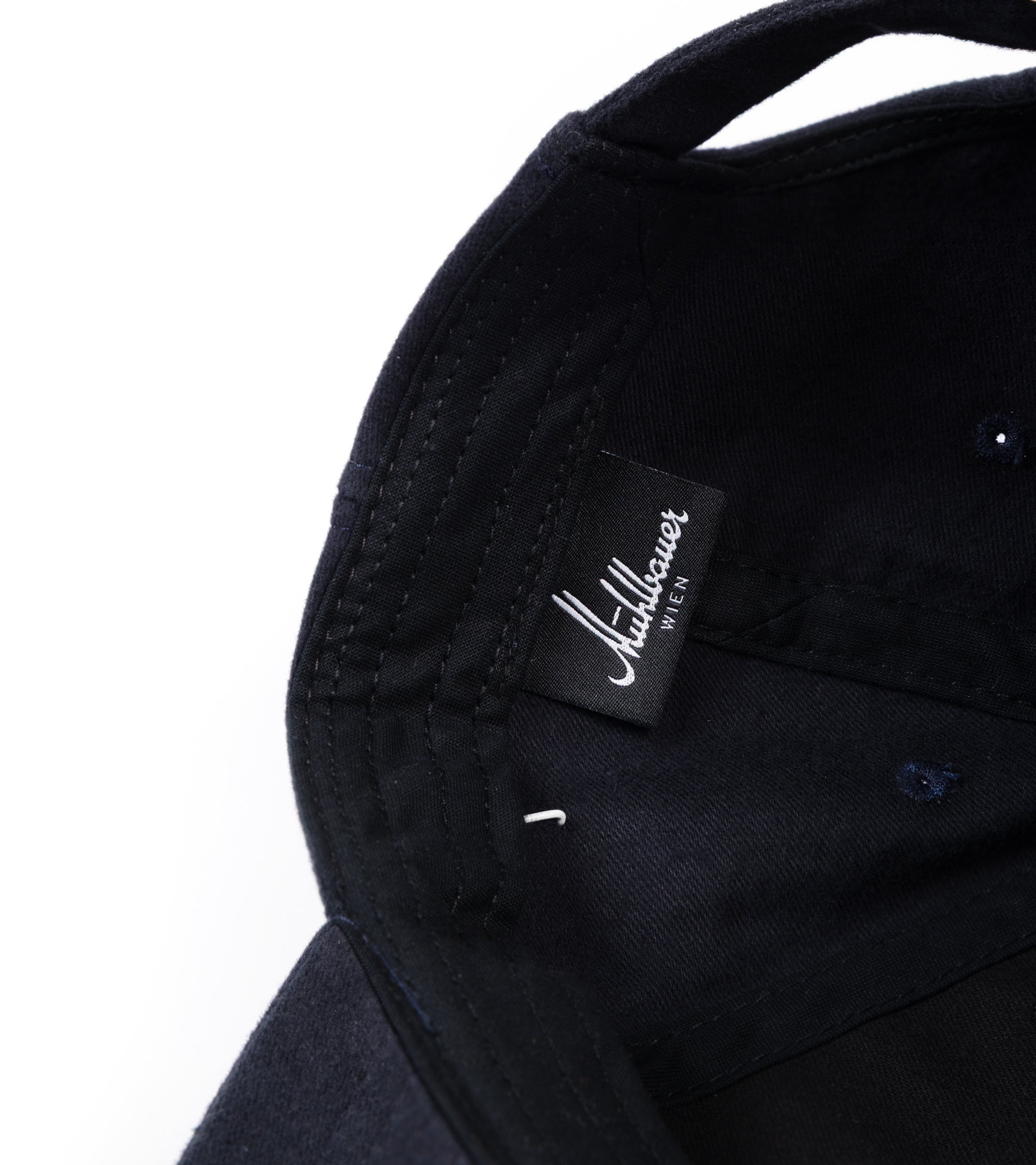 Close-up of the interior of the baseball cap, showing a black fabric brand label.