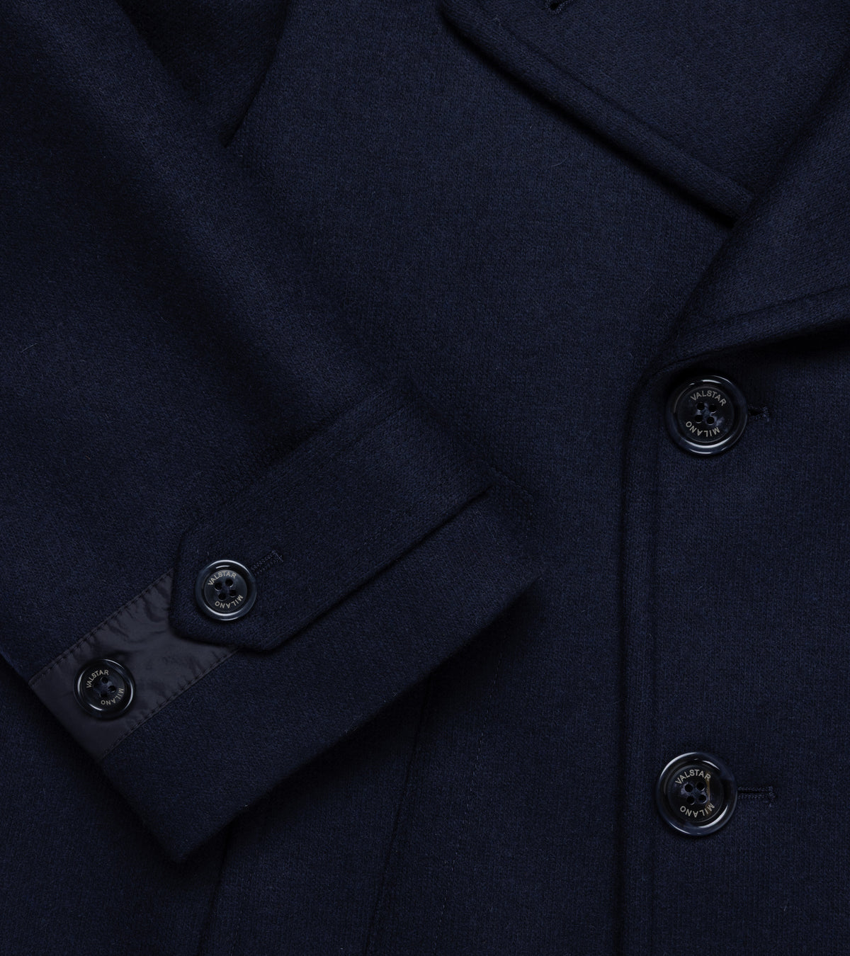 Valstar Ben Padded Wool Felt Jersey Peacoat in Navy. Close-up detail of the button-tab cuffs of the sleeve and wool blend fabric. Valstar branded buttons.