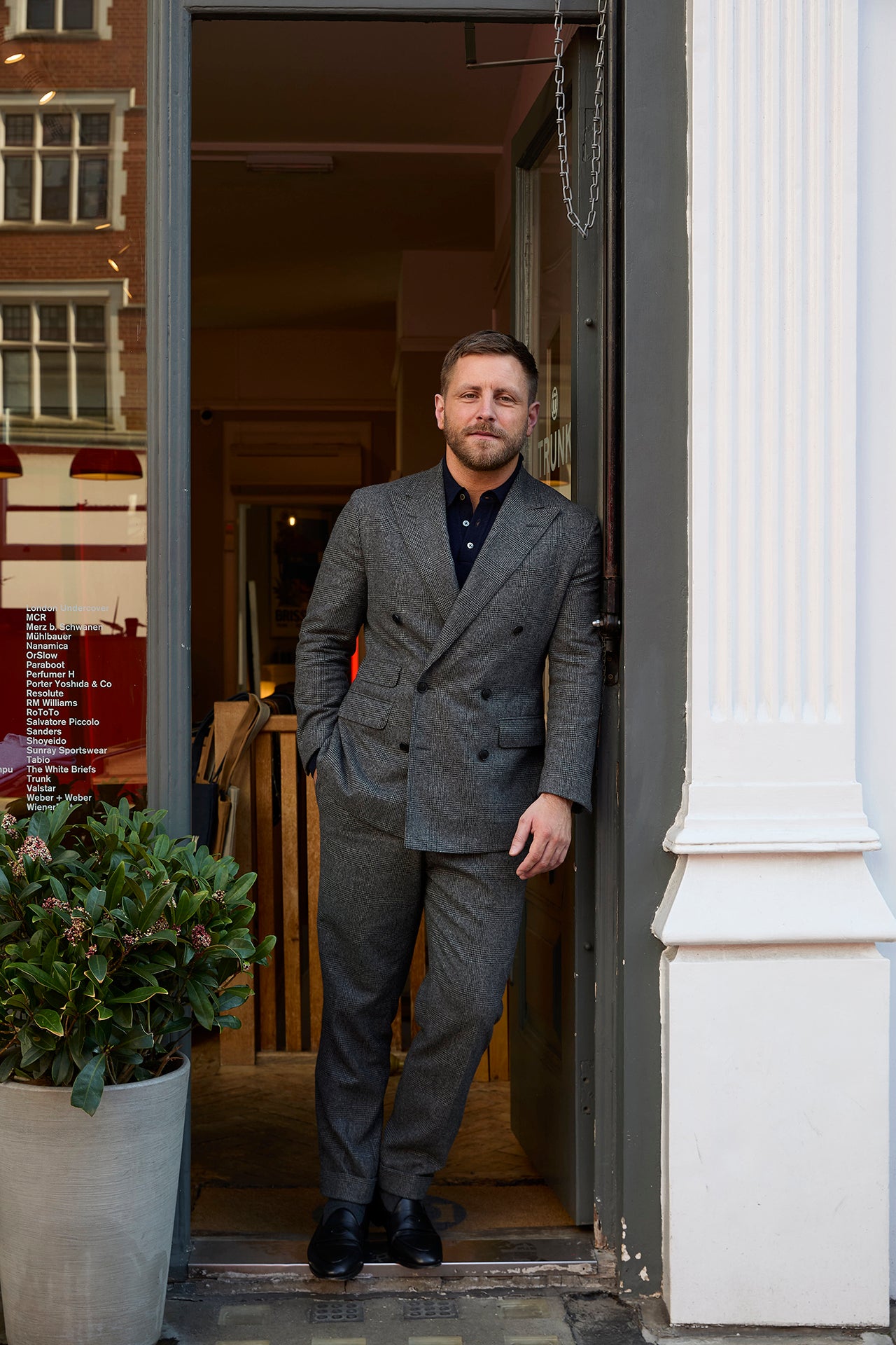 Man in a gray suit standing in an open doorway of a building.